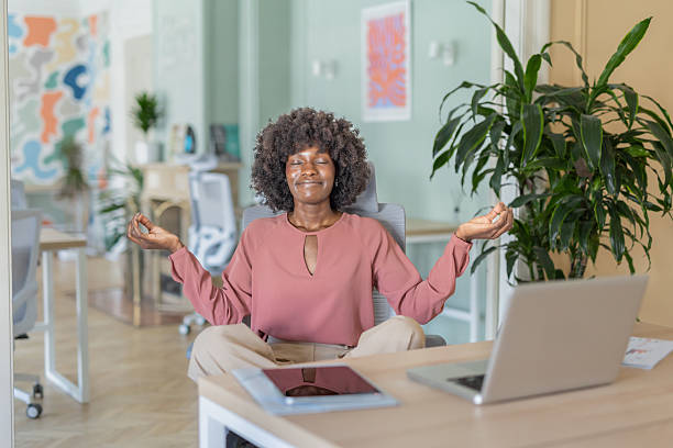 istock Tranquil woman meditating in a bright modern office 2216473919