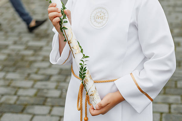 istock Young child in white communion robe holding a decorated candle during First Holy Communion. Polish Catholic tradition celebrating faith, purity, and spiritual growth. 2216477629