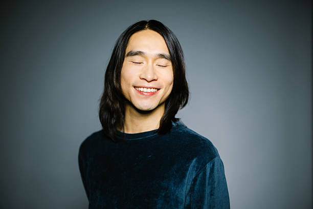 istock Asian man smiling with eyes closed on gray background 2216482403