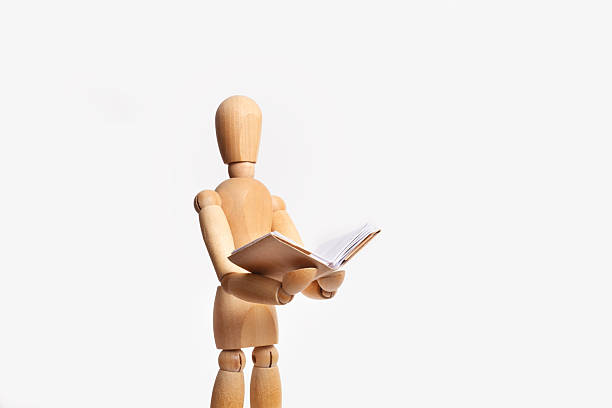 istock A wooden mannequin with a book on his hands isolated on a white background 2216483533