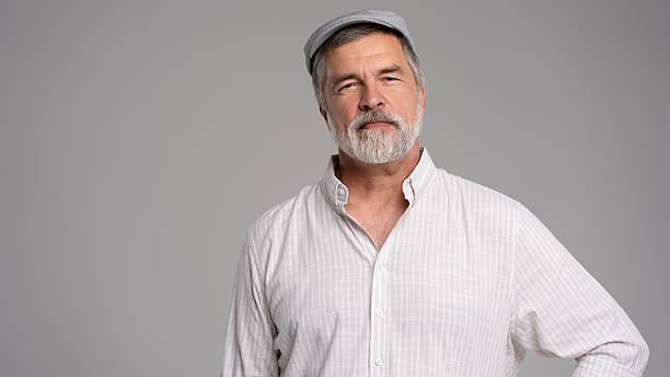 Friendly grey beard aged man in cap wear white shirt isolated on grey background