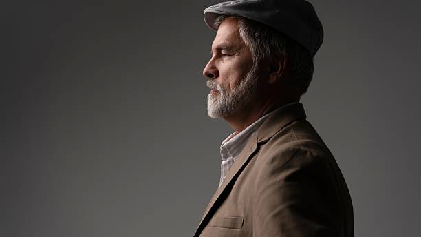 istock Mature handsome man in suit and flat cap on grey background 2216484390