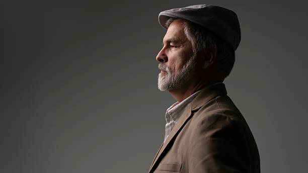 istock Mature handsome man in suit and flat cap on grey background 2216484401