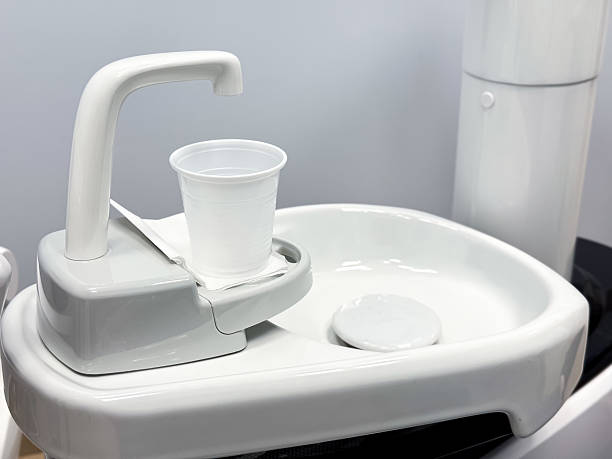 istock Modern dental equipment with cup on white sink against gray background 2216486303