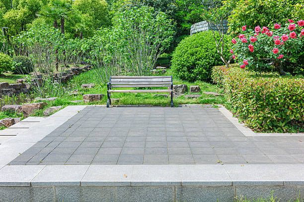 Empty park bench and stone brick pathway in the lush green garden