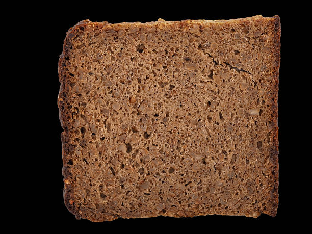 A slice of brown bread is presented, featuring a crisp crust and a soft, textured interior. The surface reveals the natural grain and nutty appearance of the loaf.