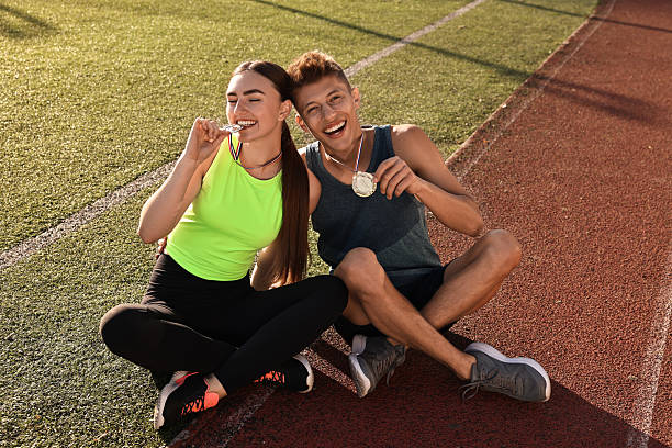 istock Happy winners with medals sitting at stadium on sunny day 2216498272