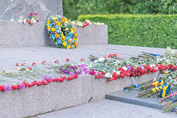 istock Memorial site, Victory Day, floral tributes, outdoor commemorative area, platform with steps, various flowers red, white, yellow, blue, clusters of bouquets, natural or artificial light, no people 2216498413