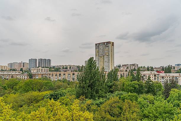 istock A serene, cloudy-sky cityscape with a tall modern building on the right and a park with vibrant trees on the left The image is taken from a distance, offering a harmonious blend of urban architectur 2216498802