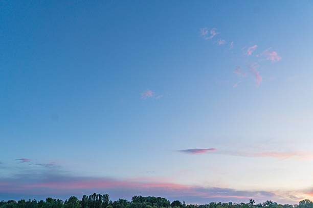 Sunrise or sunset landscape, sky gradient blue, pink, scattered clouds, calm lake, gently curved shoreline, no text, naturalistic style, focus on light and color play