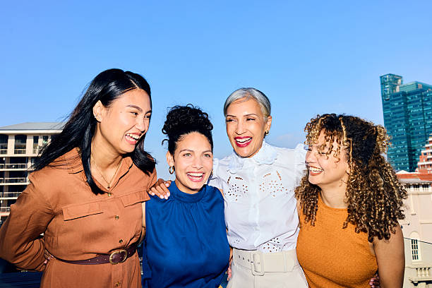 Multiracial female business professionals with cheerful expressions and arms around each other