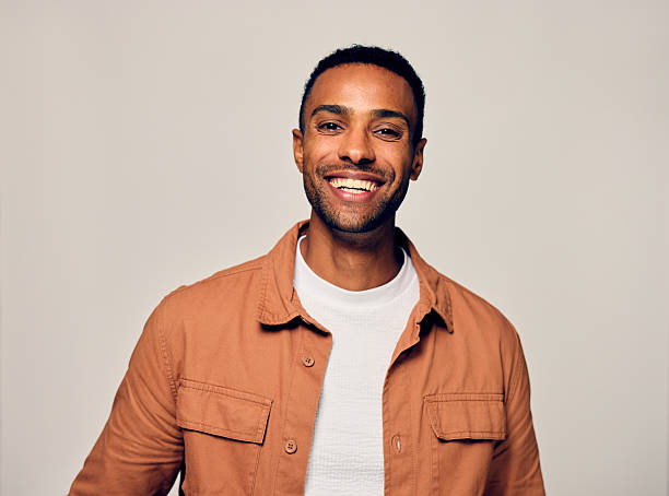 Man with black hair looking at camera with happy expression against gray background