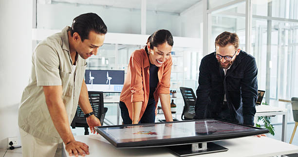 istock Happy, business people and meeting with interactive display for project, renewable energy or eco friendly development. Group, employees or team with smile or screen for wind turbine implementation 2216502461