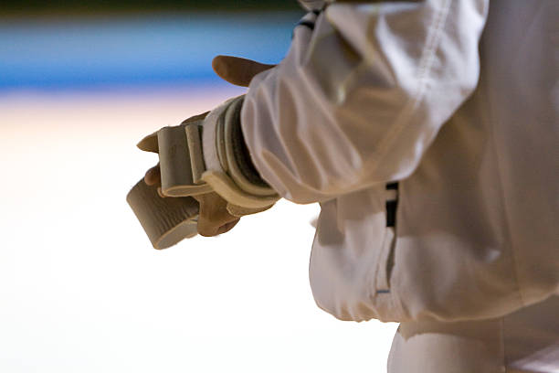 Close-up of a fencer's hand gripping their foil, showcasing the preparation and focus before a fencing match