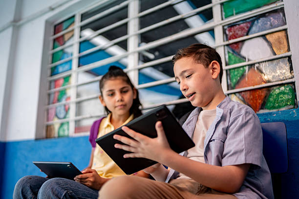 Portrait of elementary school boy holding up tablet computer