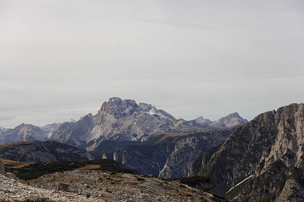A series of breathtaking views capturing the dramatic rock formations and peaks of the Dolomites in northern Italy. The rugged mountain landscapes, with their distinctive jagged summits, offer a spectacular backdrop under overcast skies. These images were taken along the hiking trails near Tre Cime di Lavaredo, showcasing the unique geology and natural beauty of this UNESCO World Heritage Site.