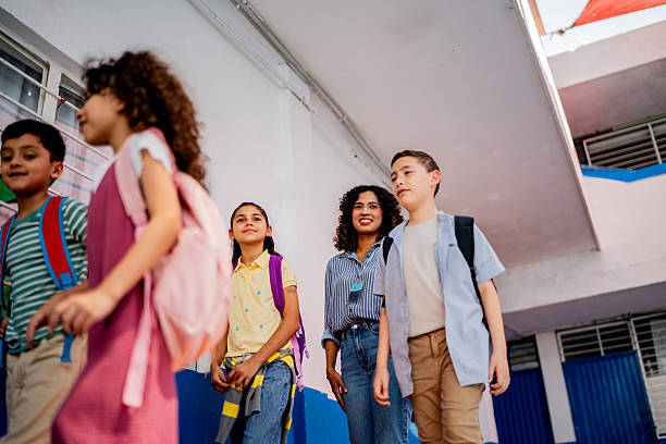 istock Teacher walking and talking to child students at school 2216508059