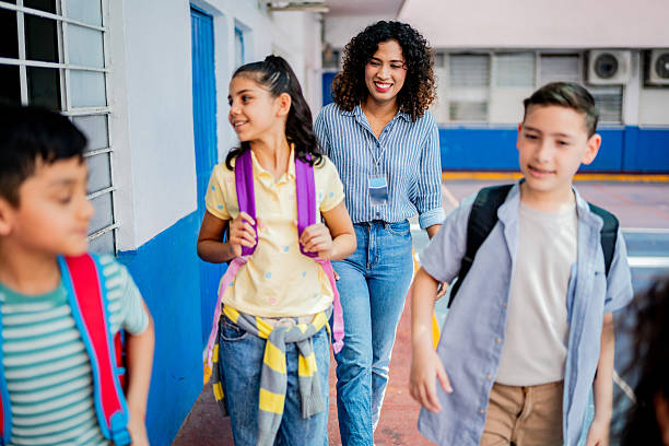 istock Teacher walking and talking to child students at school 2216508226