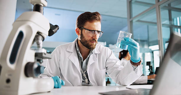 istock Scientist, man and chemistry with laptop for analysis, breakthrough or medical notes research. Biotech, laboratory and microscope with DNA for pharmaceutical RNA study or chemical experiment project 2216509076