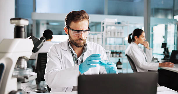 istock Scientist, man and chemistry with laptop for project, breakthrough or medical notes research. Biotech, laboratory and microscope with DNA for pharmaceutical RNA analysis or chemical experiment study 2216509097