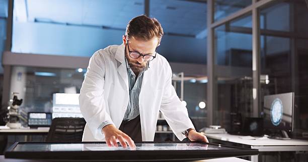 istock Scientist, man and thinking with screen for lab review, medical research or innovation. Computer table, interactive display and clinical analysis for studying science data, technology and results 2216509156