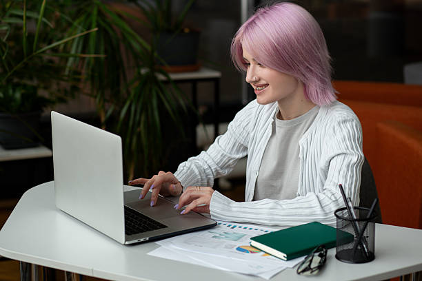 istock Young pink haired female worker working remotely using laptop, business concept 2216509577