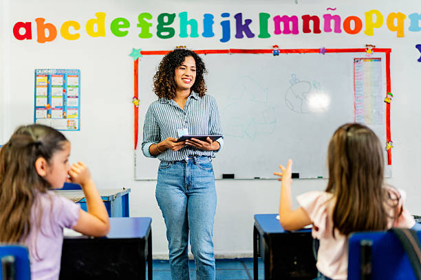 istock Young teacher woman talking to child students during class at school 2216510102