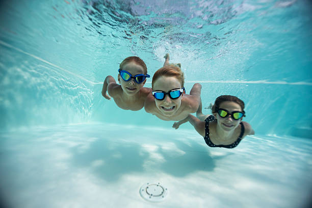 istock Three cute kids swimming underwater in a pool on a summer holiday 2216514580