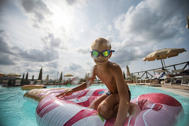 istock Little boy relaxing on an inflatable float in a sunny pool. 2216514610