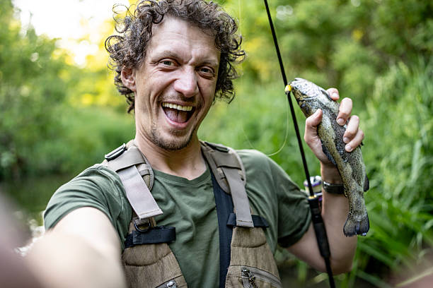Mid adult fisherman holding his catch in the river.