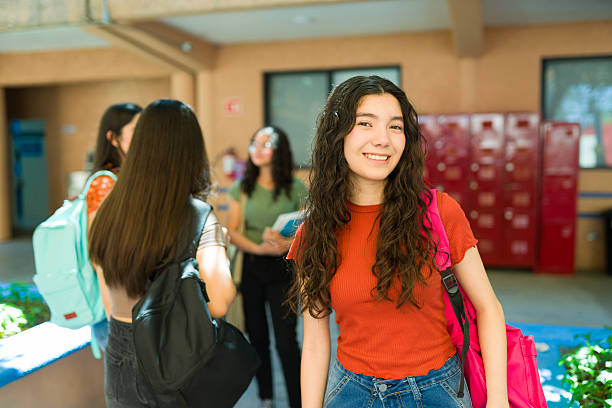 istock Cute High school student standing next to her friends in hallway 2216515197