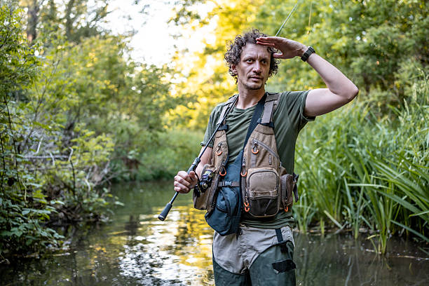istock Man Fishing in Scenic Natural River Surrounded by Dense Greenery 2216515393