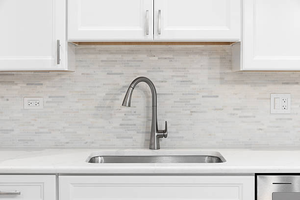 istock A kitchen faucet detail with white cabinets and tiled backsplash. 2216515408