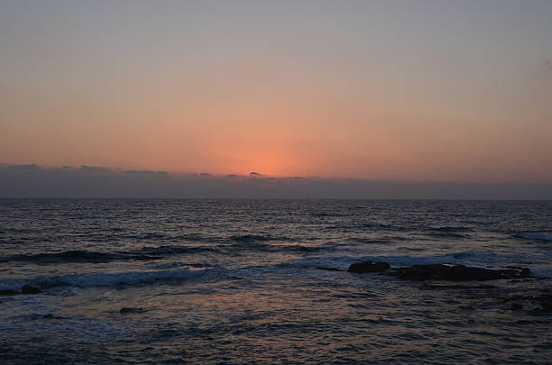 Serene ocean sunset with gentle waves and vibrant horizon.