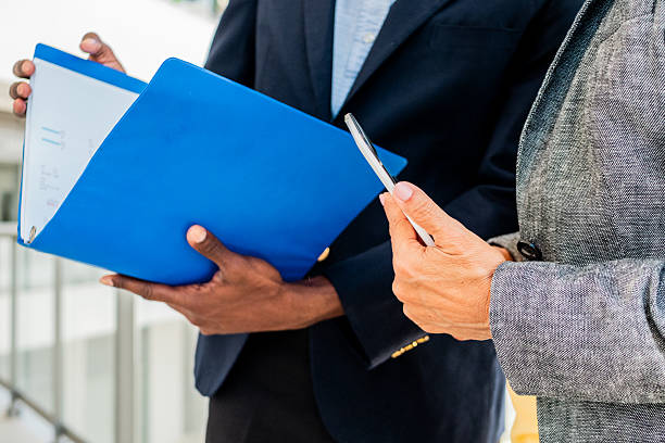 istock Close-up of coworkers holding documents and digital tablet 2216521075