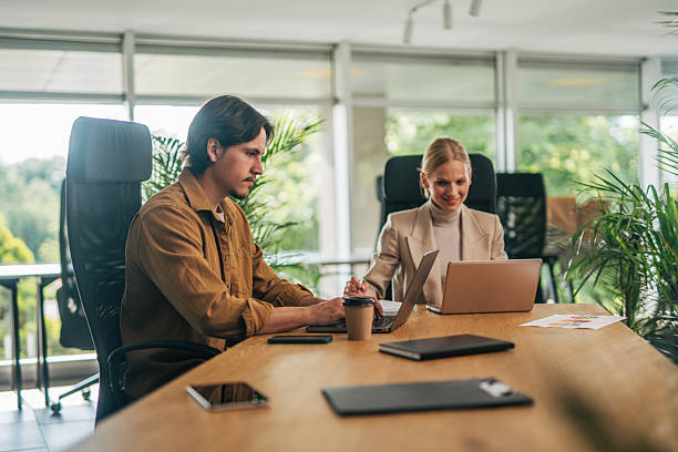 istock Two young businesspeople working on laptops in modern office 2216523883