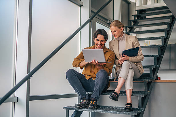 istock Two young business colleagues working on stairs with laptop and documents 2216523888