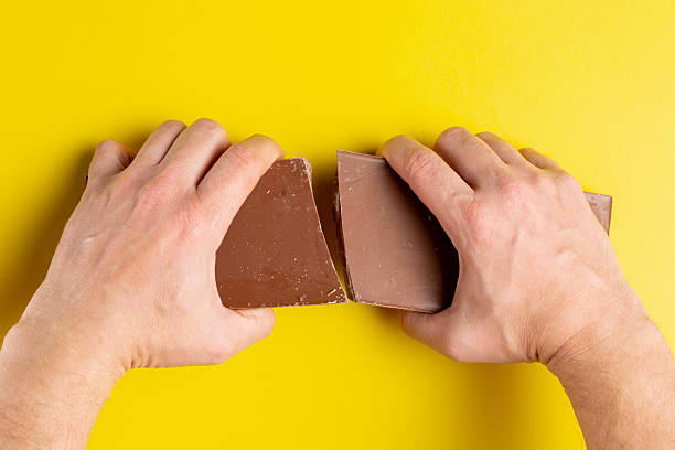 istock A man breaks a large bar of chocolate with his hands. 2216527532