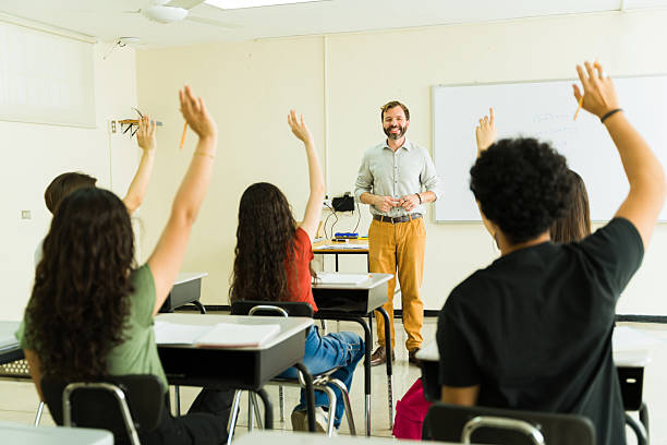Back view of male professor giving lecture to high school students in the classroom.