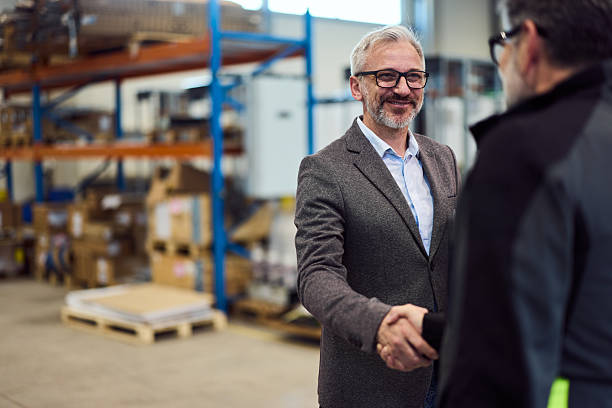 istock Business Professionals Shaking Hands in a Warehouse Setting for Partnership 2216532879