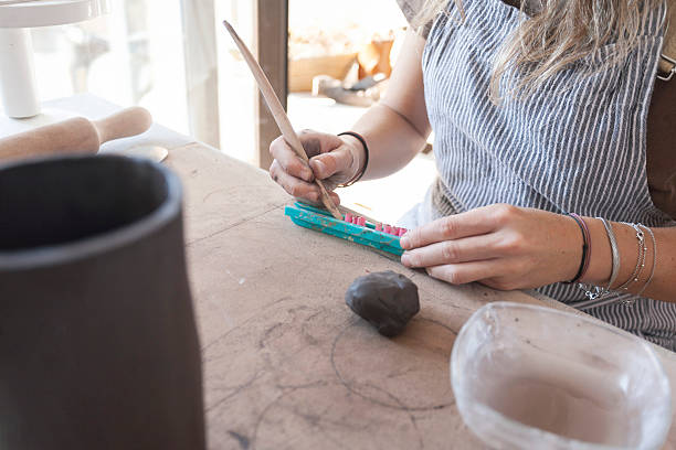istock Ceramist writing a name with a ceramic letter stamp on a piece of clay. 2216536687