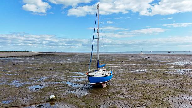 istock Blue Sailboat Grounded on Coastal Flats 2216540436