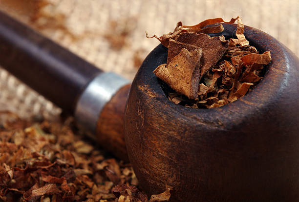 istock Smoking pipe and tobacco on wooden table. close up 2216544962