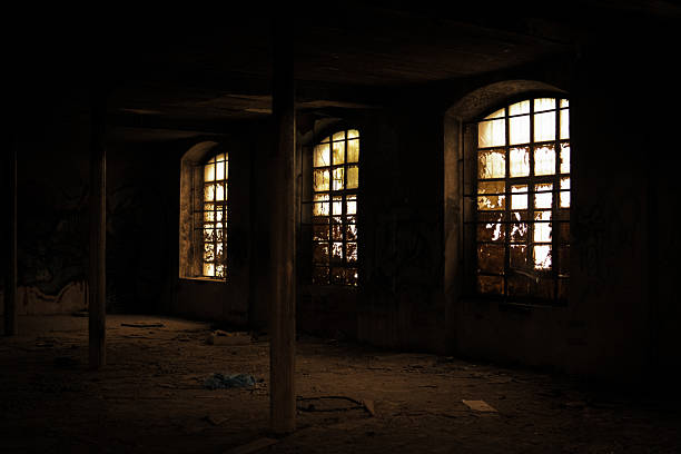 A worn building facade featuring multiple aged windows, including a large central frame with broken glass and peeling paint. Exposed brick and cracked plaster add to the distressed, timeworn character. The muted colors and rough textures emphasize decay and historic charm.