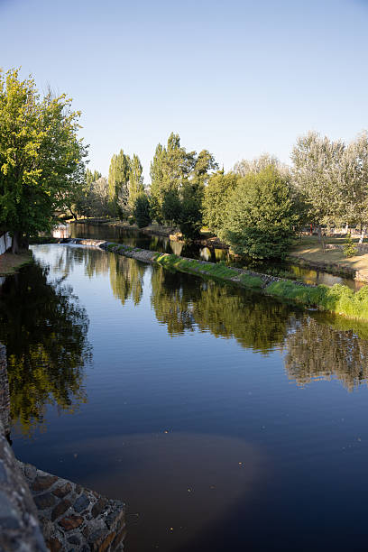 istock A serene river scene featuring a small stone dam with water gently cascading over the edge, surrounded by greenery and reflected sunlight, creating a peaceful and natural atmosphere. Serta, Portugal. 2216547009