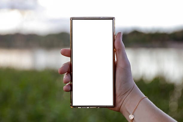 istock Woman hand holding a phone with blank white screen with copy space. In the background blurred lake and sky. 2216552536