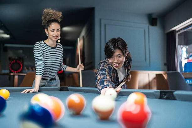 Young people playing billiards in a pool hall