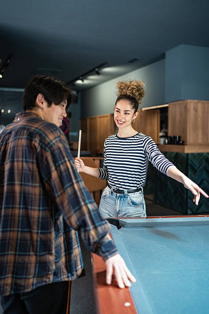 istock Young couple playing billiards and having fun together in a pool hall 2216553138
