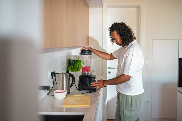 istock Mid Adult Hispanic Male Making a Smoothie in Modern Kitchen 2216553752