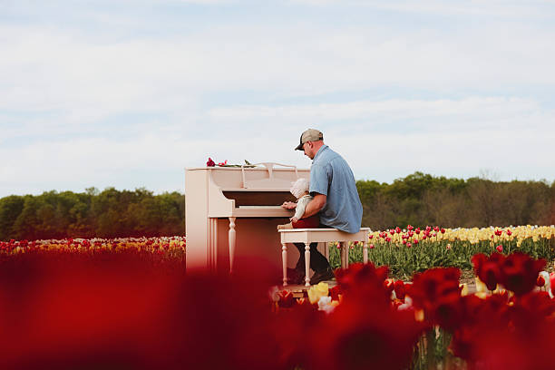 A man playing piano with his baby daughter in a picturesque tulip field. The baby is 6 months old. Shot with a Canon 5D Mark IV.